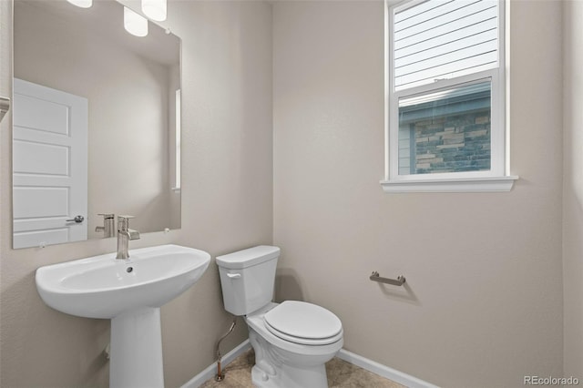 bathroom with tile patterned flooring, sink, a wealth of natural light, and toilet