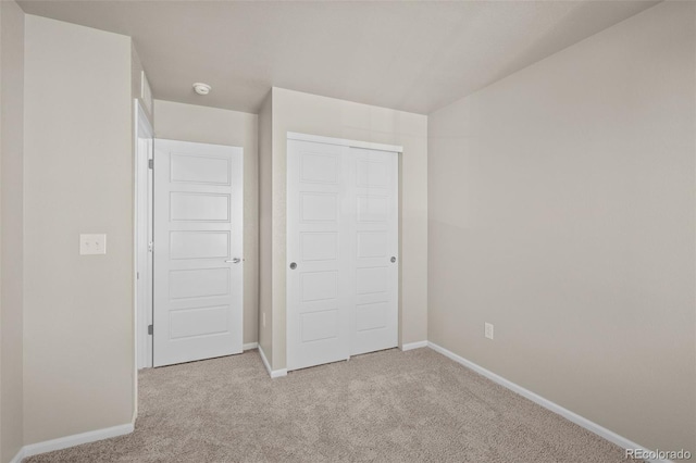 unfurnished bedroom featuring light colored carpet and a closet