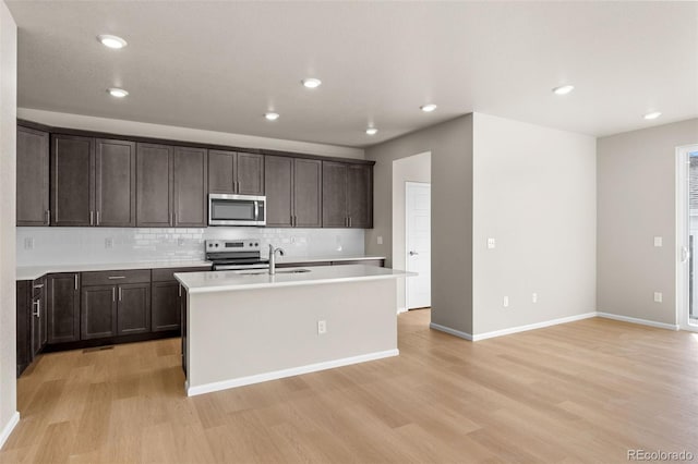 kitchen featuring sink, light hardwood / wood-style flooring, an island with sink, and appliances with stainless steel finishes