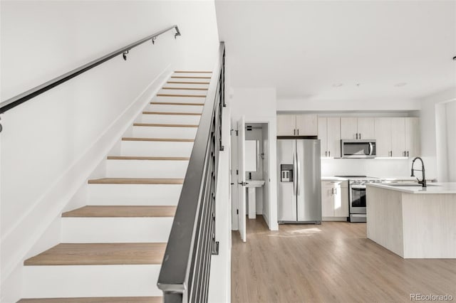 stairs featuring hardwood / wood-style floors and sink