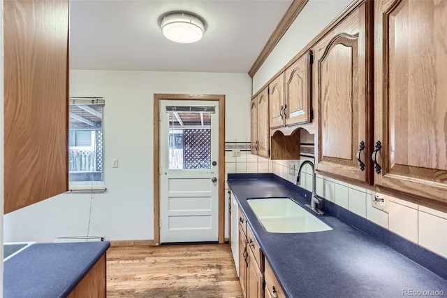 7995 Robin Ln, Denver, CO 80221 - kitchen featuring a sink, dark countertops, light wood finished floors, and backsplash
