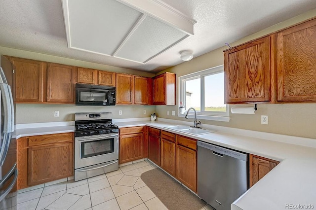 4863 Quail Ct, Frederick, CO 80504 - kitchen featuring stainless steel appliances, a sink, brown cabinetry, light countertops, and light tile patterned flooring