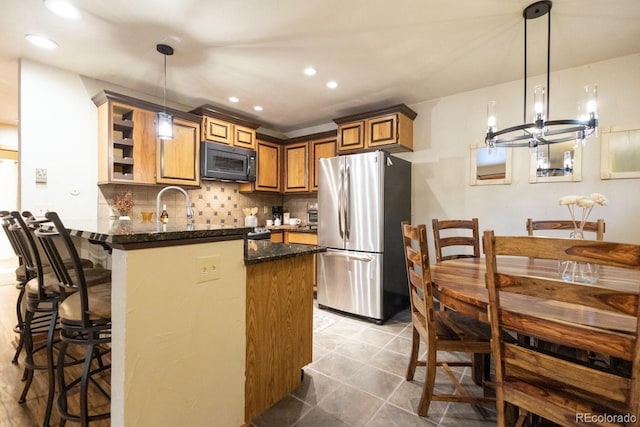 145 Arapahoe Rd Unit 102, Winter Park, CO 80482 - kitchen featuring freestanding refrigerator, black microwave, a peninsula, a chandelier, and a kitchen bar