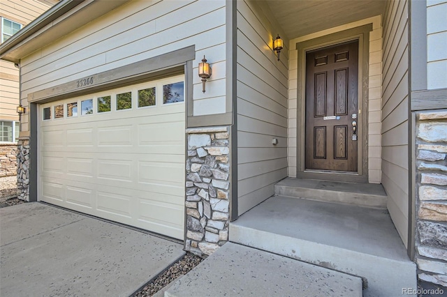 property entrance with a garage and stone siding