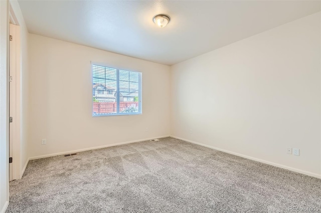 carpeted spare room featuring visible vents and baseboards