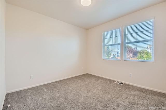 carpeted spare room featuring visible vents and baseboards