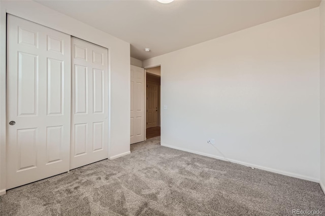 unfurnished bedroom with a closet, carpet flooring, and baseboards