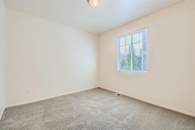 spare room with carpet floors, visible vents, and baseboards