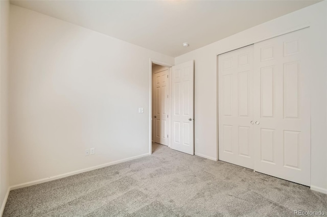 unfurnished bedroom featuring light colored carpet and a closet