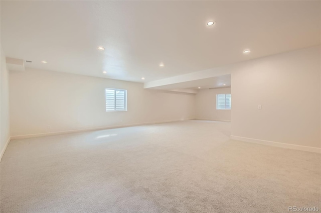 spare room with recessed lighting, plenty of natural light, baseboards, and light colored carpet