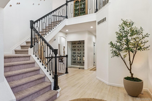 interior space with a towering ceiling, baseboards, visible vents, and wood finished floors