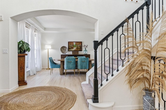 entryway with wood finished floors, baseboards, arched walkways, and stairs