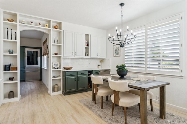 dining room featuring arched walkways, light wood-style floors, and an inviting chandelier