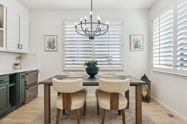 dining room featuring baseboards, light wood-style floors, a chandelier, and visible vents