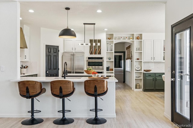kitchen featuring a peninsula, a kitchen bar, a sink, open shelves, and stainless steel appliances