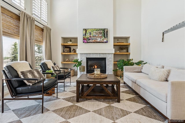 living area with a fireplace, built in features, and a towering ceiling
