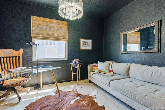 living area featuring an inviting chandelier, a textured wall, and wood finished floors