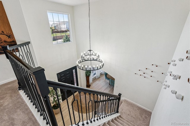 stairs featuring baseboards, carpet flooring, and a chandelier
