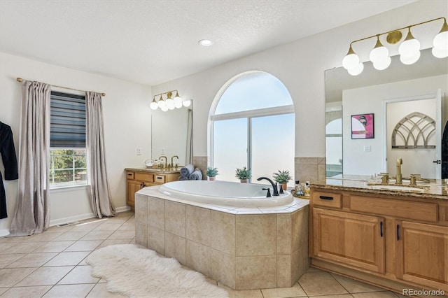 bathroom featuring tile patterned flooring, a garden tub, two vanities, and a sink