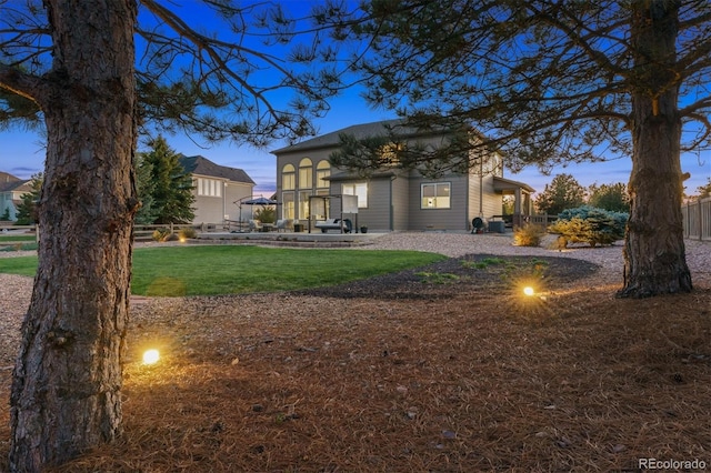 back of property at dusk with a lawn
