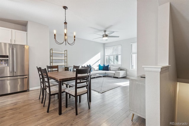 dining room featuring ceiling fan with notable chandelier and light hardwood / wood-style flooring