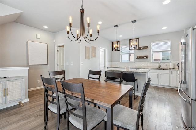 dining space featuring an inviting chandelier, sink, and light hardwood / wood-style flooring