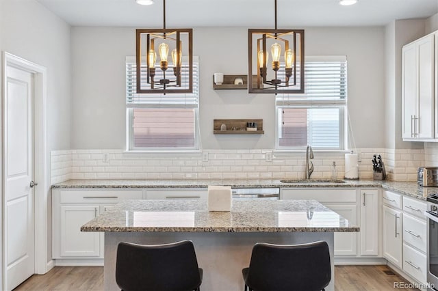 kitchen with white cabinetry, sink, decorative light fixtures, and a notable chandelier