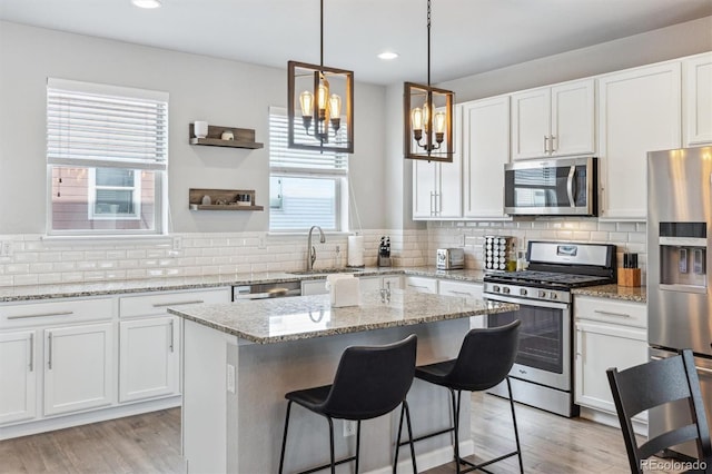 kitchen featuring light stone countertops, white cabinetry, appliances with stainless steel finishes, and a center island