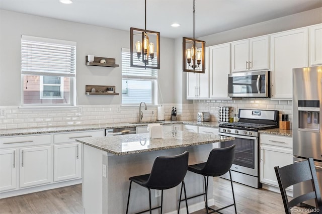 4260 E Warren Ave Unit 5, Denver, CO 80222 - kitchen featuring appliances with stainless steel finishes, plenty of natural light, white cabinets, a kitchen island, and recessed lighting