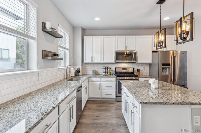 4260 E Warren Ave Unit 5, Denver, CO 80222 - kitchen with appliances with stainless steel finishes, open shelves, a sink, white cabinetry, and decorative backsplash
