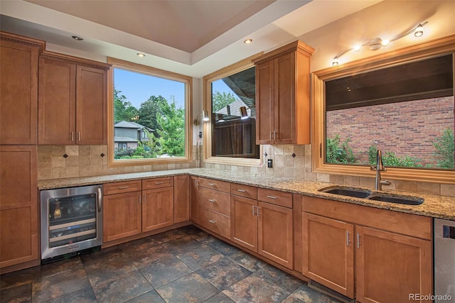 kitchen featuring light stone counters, beverage cooler, sink, and tasteful backsplash