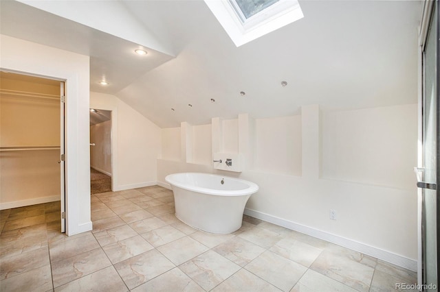 bathroom with vaulted ceiling with skylight and a tub