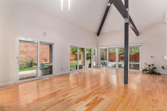 unfurnished living room featuring light hardwood / wood-style flooring, beam ceiling, and high vaulted ceiling