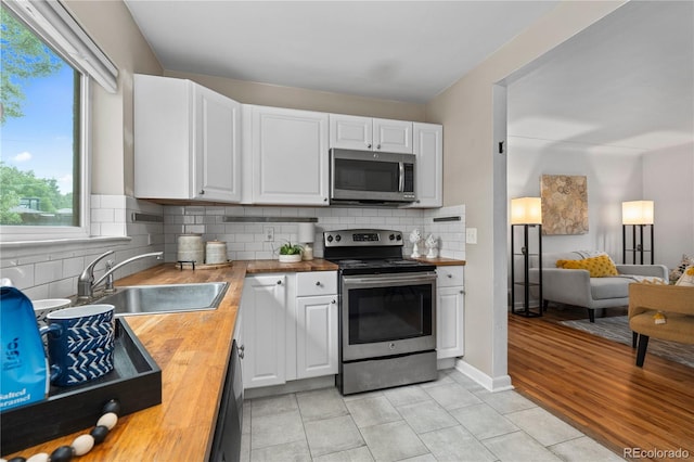 1540 Filbert Ct, Denver, CO 80220 - kitchen with stainless steel appliances, wooden counters, a sink, and white cabinets