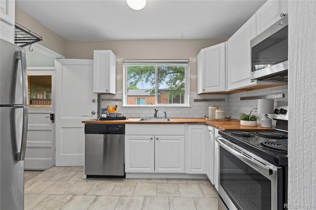 1540 Filbert Ct, Denver, CO 80220 - kitchen featuring appliances with stainless steel finishes, a sink, backsplash, white cabinets, and butcher block counters