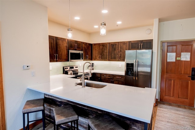 23110 US Highway 6 Unit 5040, Keystone, CO 80435 - kitchen with stainless steel appliances, backsplash, dark brown cabinetry, a breakfast bar area, and light countertops