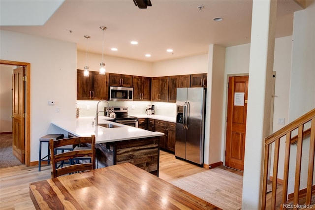 23110 US Highway 6 Unit 5040, Keystone, CO 80435 - kitchen with stainless steel appliances, light wood-style floors, a peninsula, dark brown cabinetry, and recessed lighting