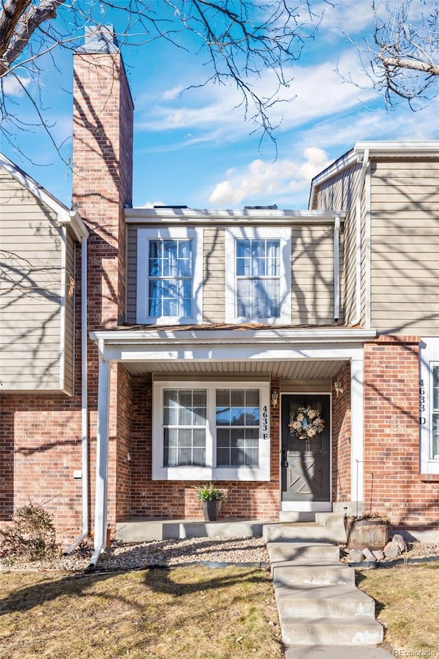 doorway to property featuring brick siding and a chimney