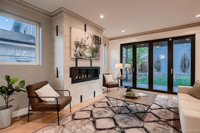 living room featuring crown molding, wood-type flooring, a fireplace, and french doors