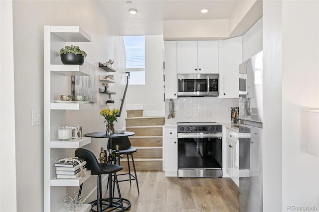 5363 W 14th Ave, Lakewood, CO 80214 - kitchen with appliances with stainless steel finishes, light wood-style flooring, white cabinets, tasteful backsplash, and light countertops