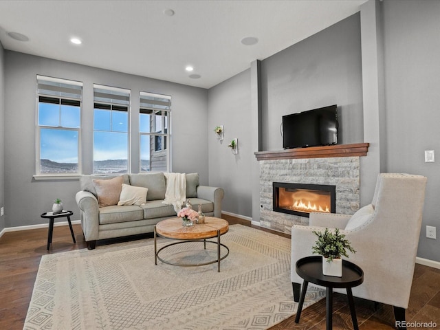 living room featuring wood finished floors, baseboards, a fireplace, and recessed lighting