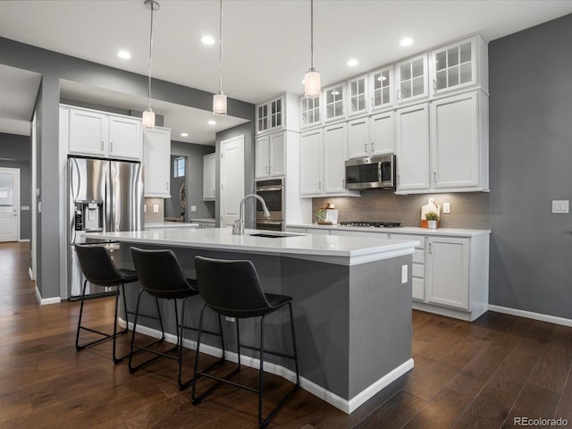 kitchen with a sink, stainless steel appliances, recessed lighting, an island with sink, and backsplash
