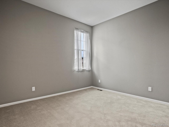 spare room featuring baseboards, visible vents, and carpet