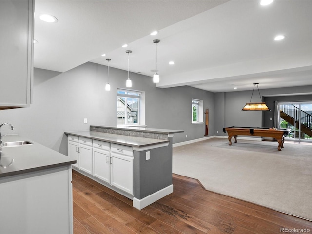 kitchen with recessed lighting, a sink, open floor plan, a peninsula, and white cabinets