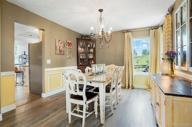 2061 Chesapeake Pl, Highlands Ranch, CO 80126 - dining space featuring a chandelier, wood finished floors, a wainscoted wall, and a textured ceiling