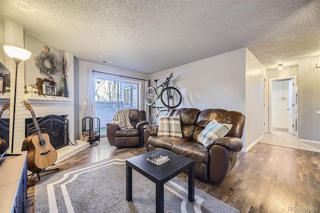 living room with a textured ceiling, a fireplace, and wood finished floors