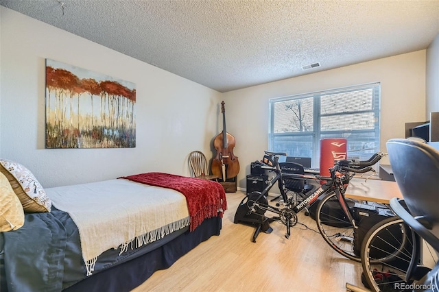 bedroom featuring a textured ceiling, visible vents, and wood finished floors