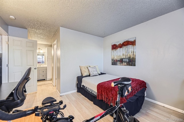 bedroom with a textured ceiling, baseboards, and wood finished floors