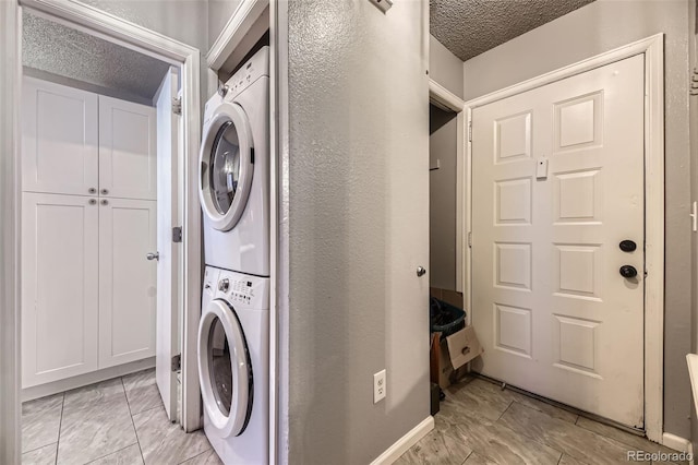 laundry room featuring a textured ceiling, stacked washer and dryer, and laundry area