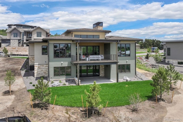 back of house featuring a patio, a balcony, and a lawn